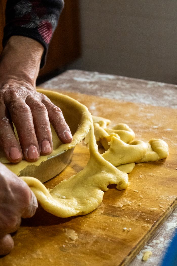 services-img Hands shaping pie crust dough on a wooden board for baking. Perfect for culinary content.