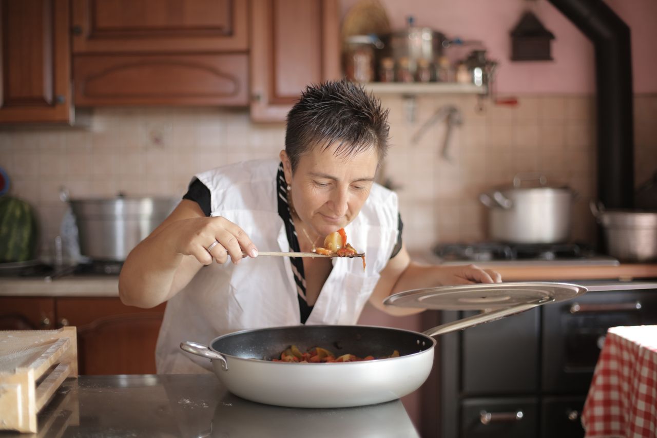 ours-journey A woman savoring the aroma of a freshly cooked dish in a cozy kitchen setting.