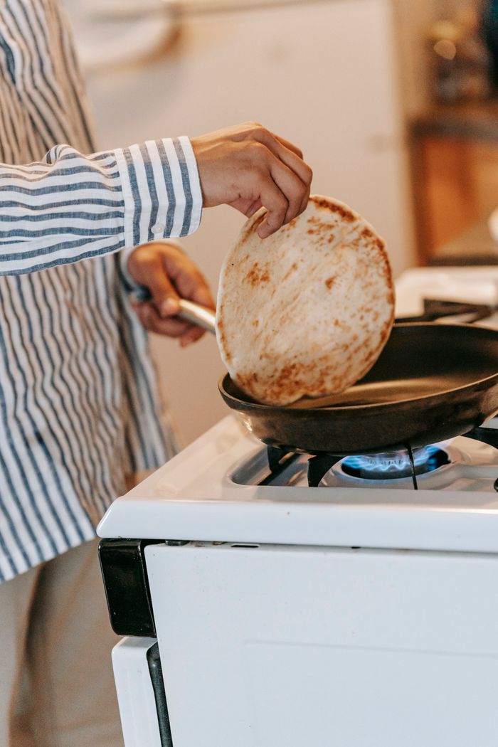 why-choose-us Crop unrecognizable person in striped shirt cooking pancakes on blurred background of kitchen